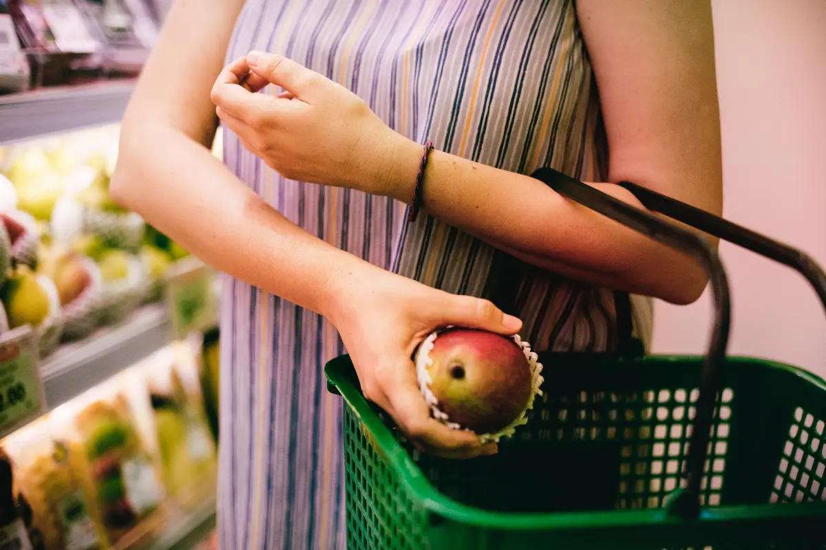 Donna che mette un mango nel carrello